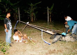 Narong Hinon lays on the ground as police search his motorcycle for drugs.